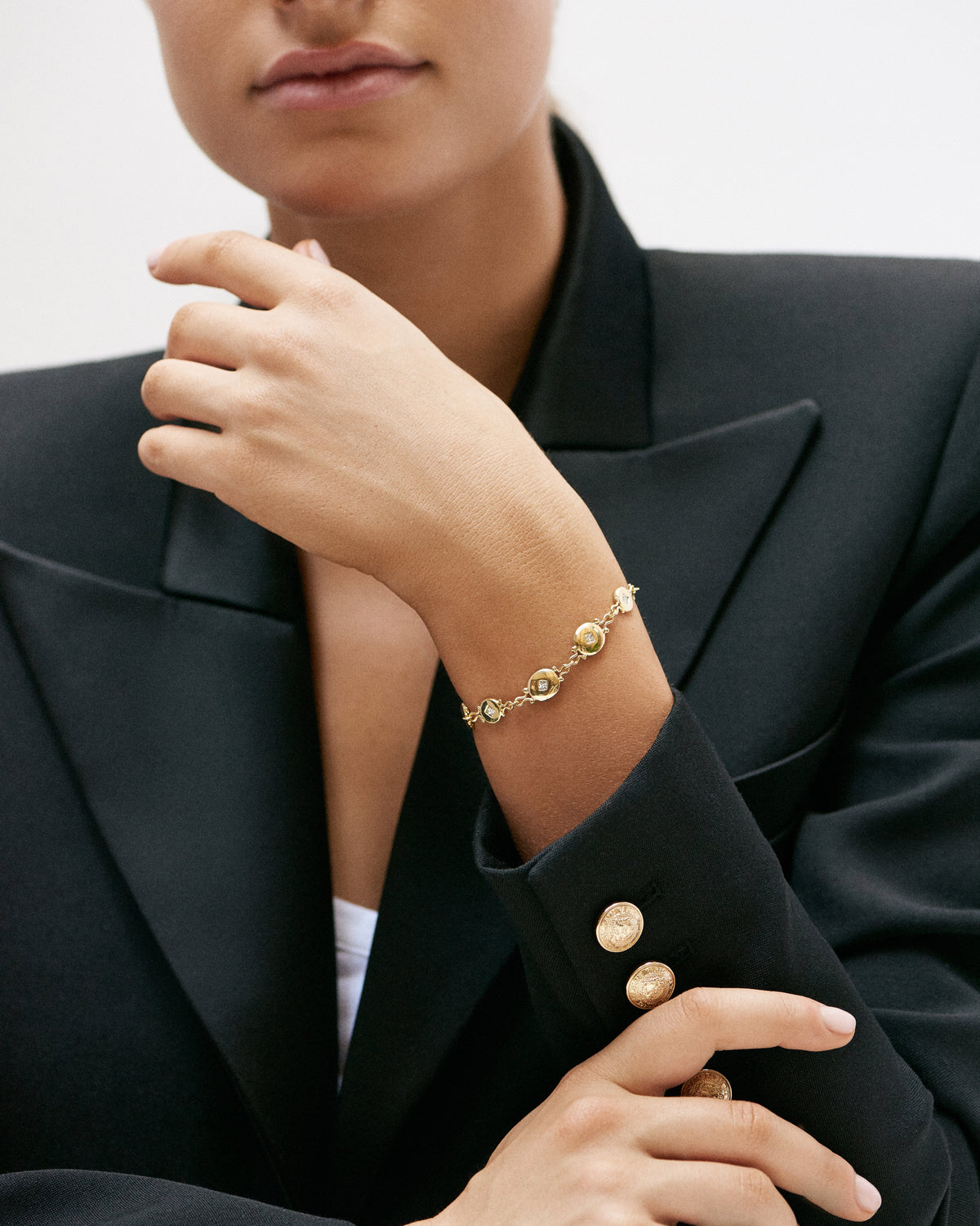 A woman in a black blazer wearing the Libertine Medallion Bracelet in gold