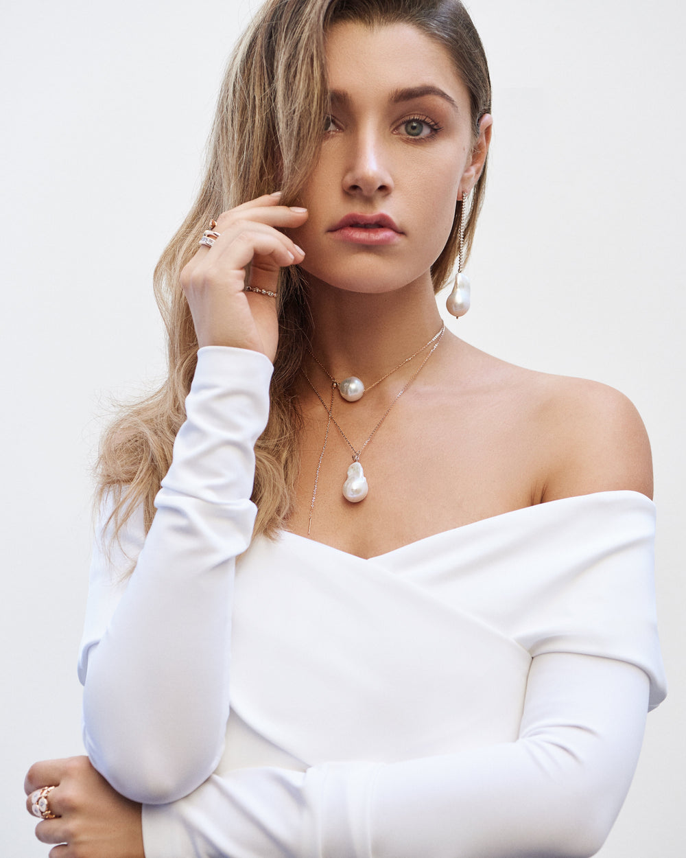 A woman in a white off-the-shoulder top wearing an Ilene Joy baroque pearl necklace