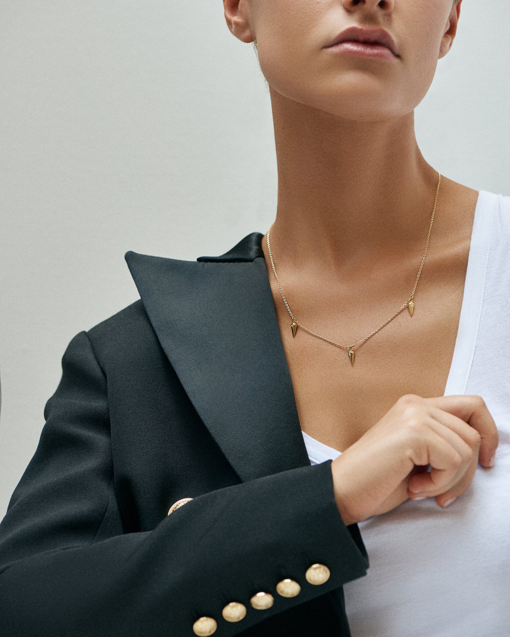 A woman in a black double-breasted blazer wearing a fine Ilene Joy gold necklace