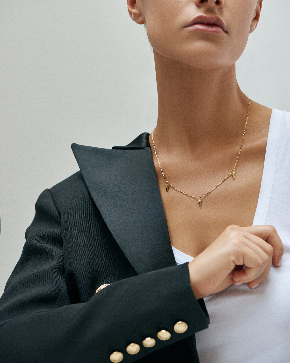 A woman in a black double-breasted blazer wearing a fine Ilene Joy gold necklace
