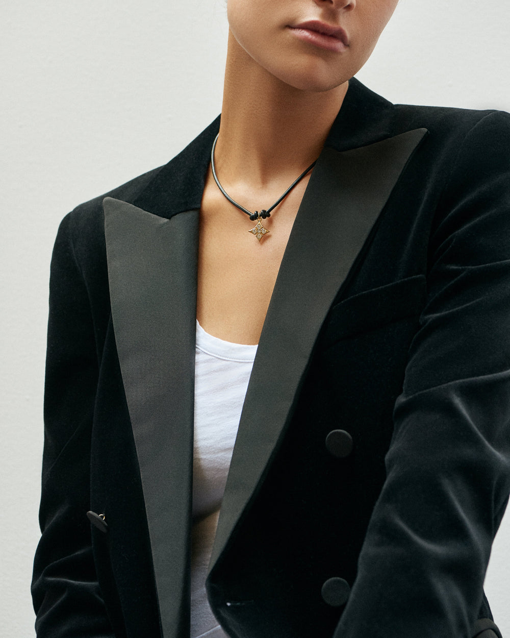 A woman in a black velvet blazer wearing the Black Butter Clover Necklace