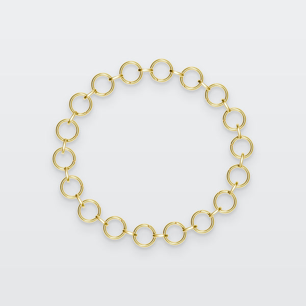 Special Circle Bracelet in solid gold, photographed flat on a pale grey studio surface
