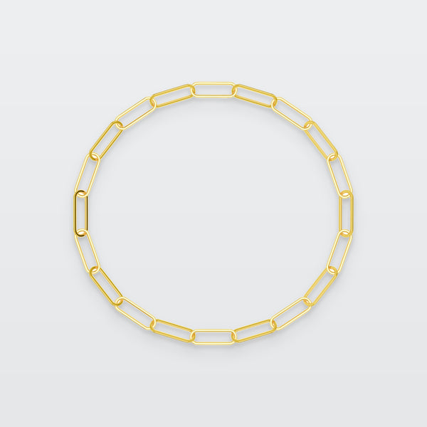 Thin Paperclip Chain Bracelet in solid gold, photographed flat on a pale grey studio surface